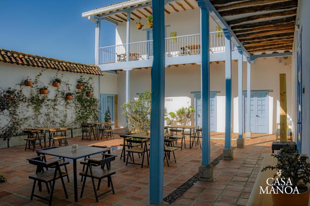 un patio con mesas y sillas frente a un edificio en Casa Manoa en Sesquilé