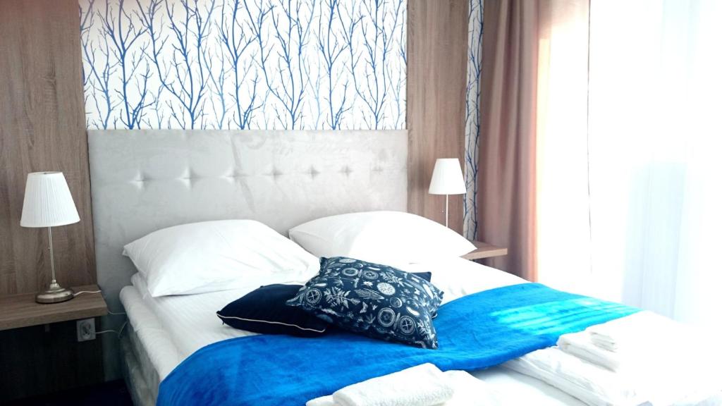 a bed with a blue blanket and pillows on it at Willa Długa No. 4 Bed & Breakfast in Gdynia