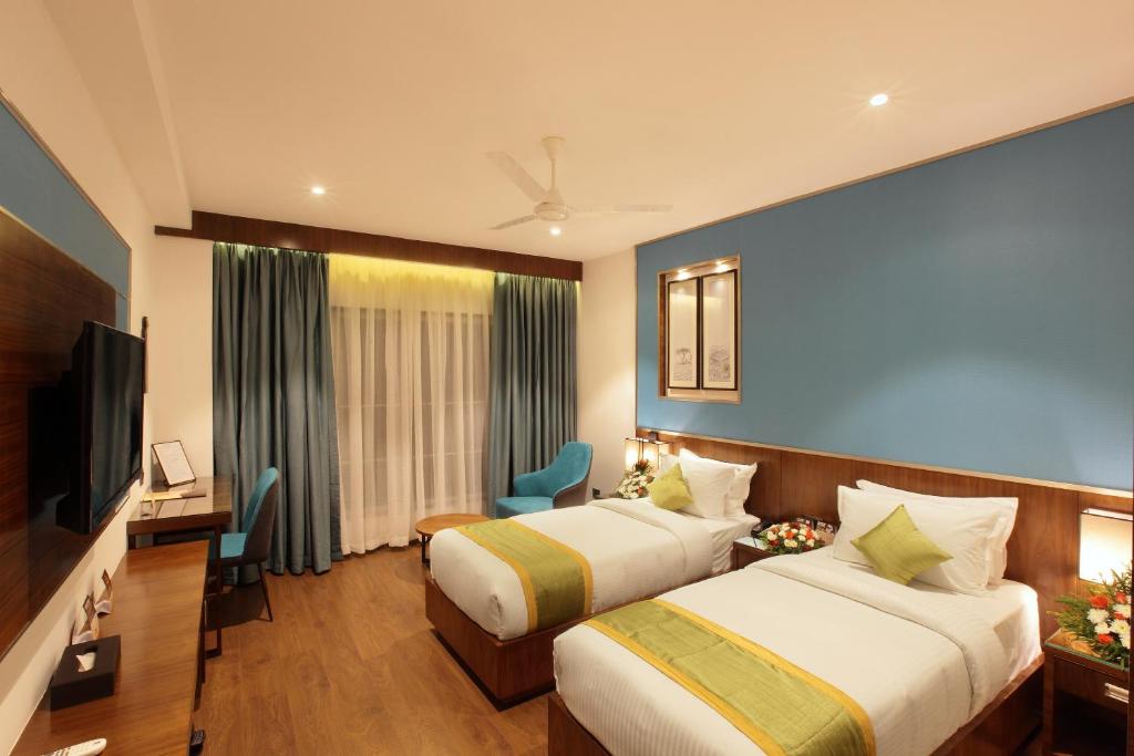Cette chambre comprend deux lits et une télévision. dans l'établissement Hotel Ceasar Palace, à Thodupuzha