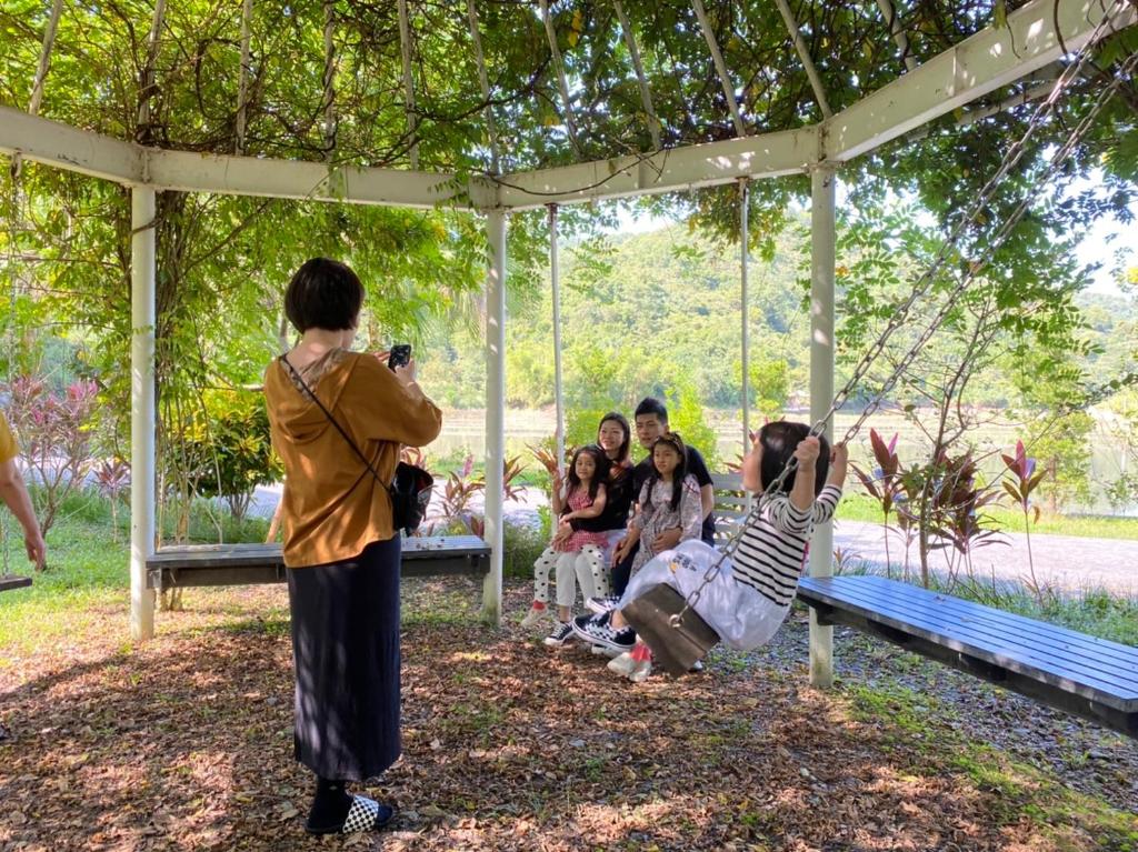 a woman taking a picture of people sitting on a swing at 光腳丫宜蘭民宿 in Dongshan