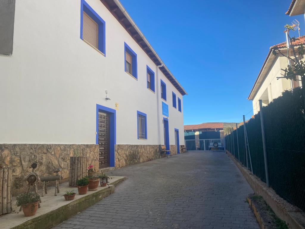 eine Straße mit einem weißen Gebäude mit blauen Türen in der Unterkunft Apartamentos Rurales Hermanos Alcalá in Ibdes