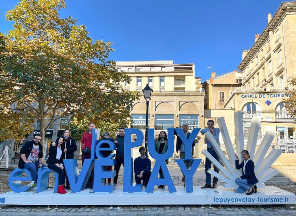 Un groupe de personnes debout devant un panneau qui dit joyeux jour dans l'établissement ibis budget Le Puy En Velay, au Puy-en-Velay