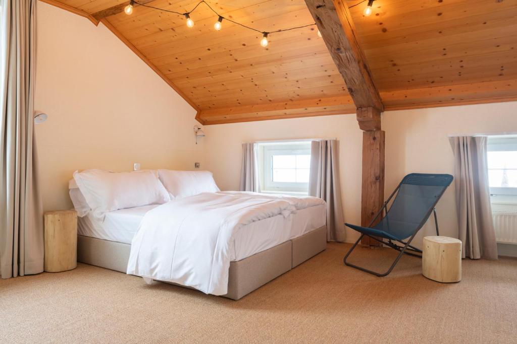1 dormitorio con 1 cama y 1 silla en Peanut Mountain Lodge & Le Communal en Val dʼIlliez