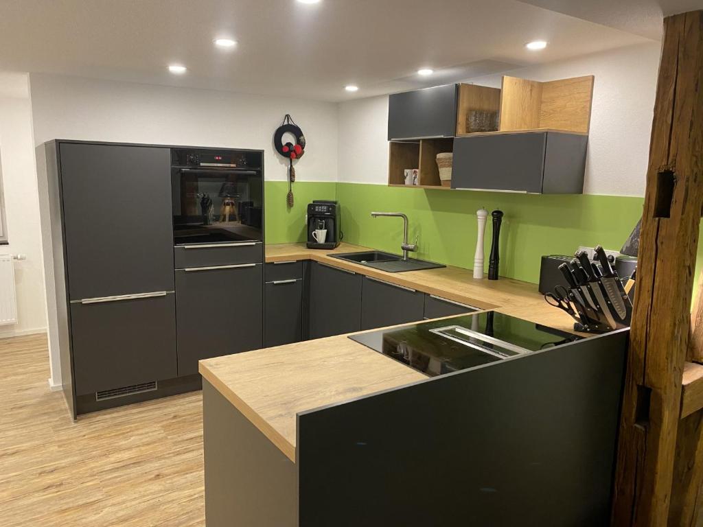 a kitchen with black appliances and green walls at Haus Schiltach in Schramberg