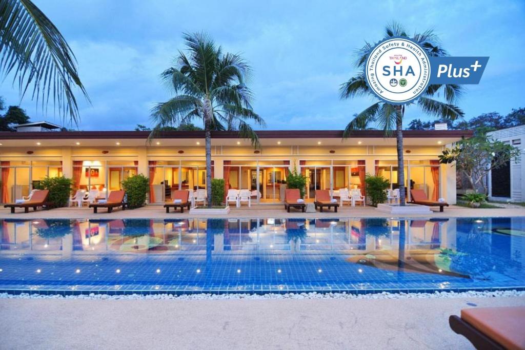 a hotel with a swimming pool in front of a building at Phuket Sea Resort SHA Extra Plus in Rawai Beach