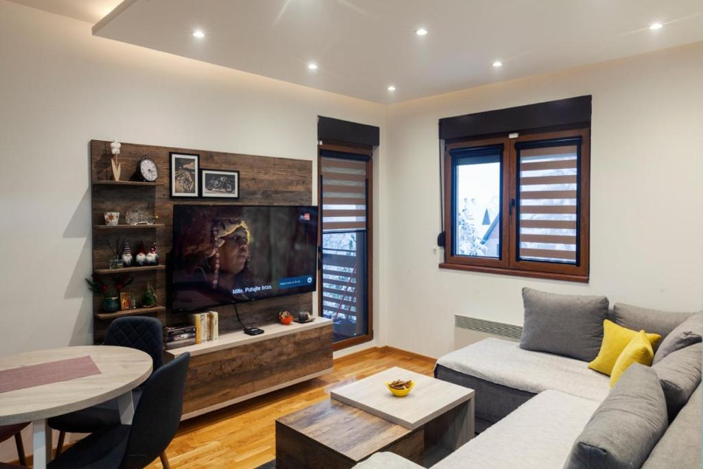 uma sala de estar com um sofá e uma televisão em Per silvas apartman i spa em Zlatibor