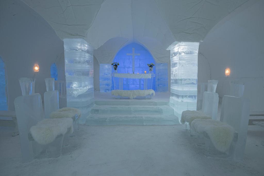 a white room with white chairs and a blue door at Sorrisniva Igloo Hotel in Alta