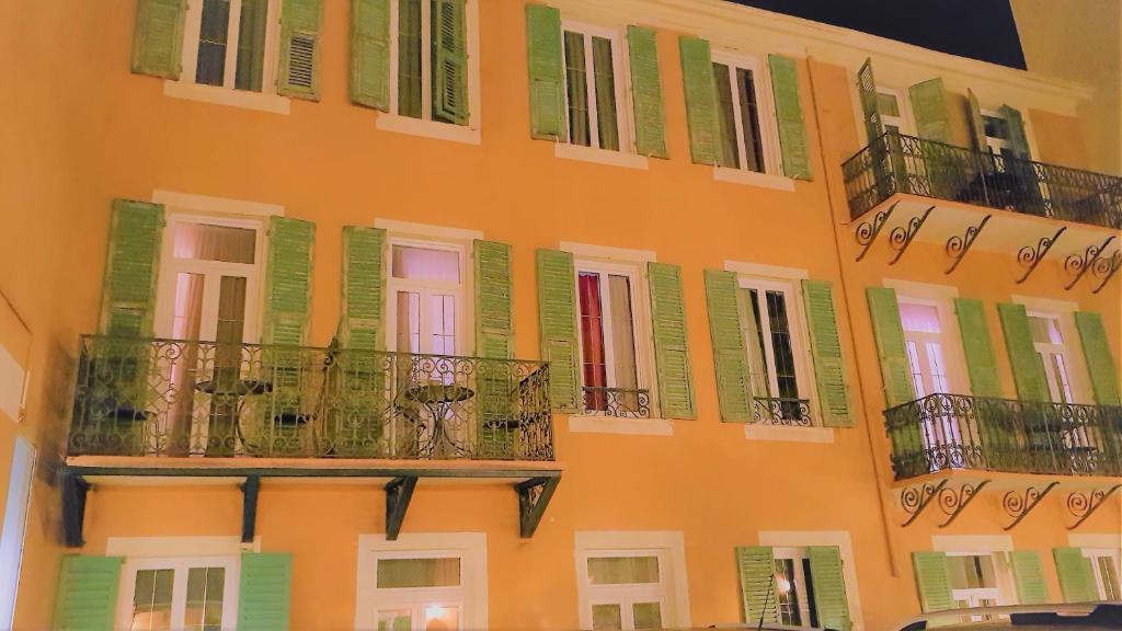 an orange building with green shuttered windows and balconies at Hôtel restaurant Oasis in Nice