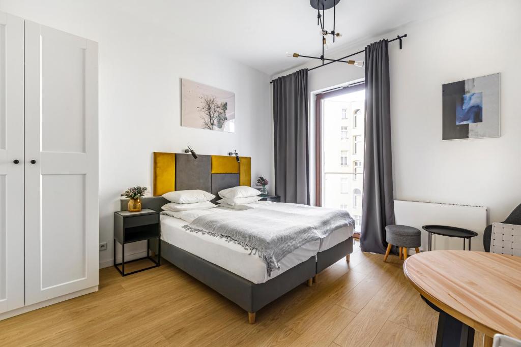 a bedroom with a bed and a table and a window at Homewell Apartments Żelazko in Poznań