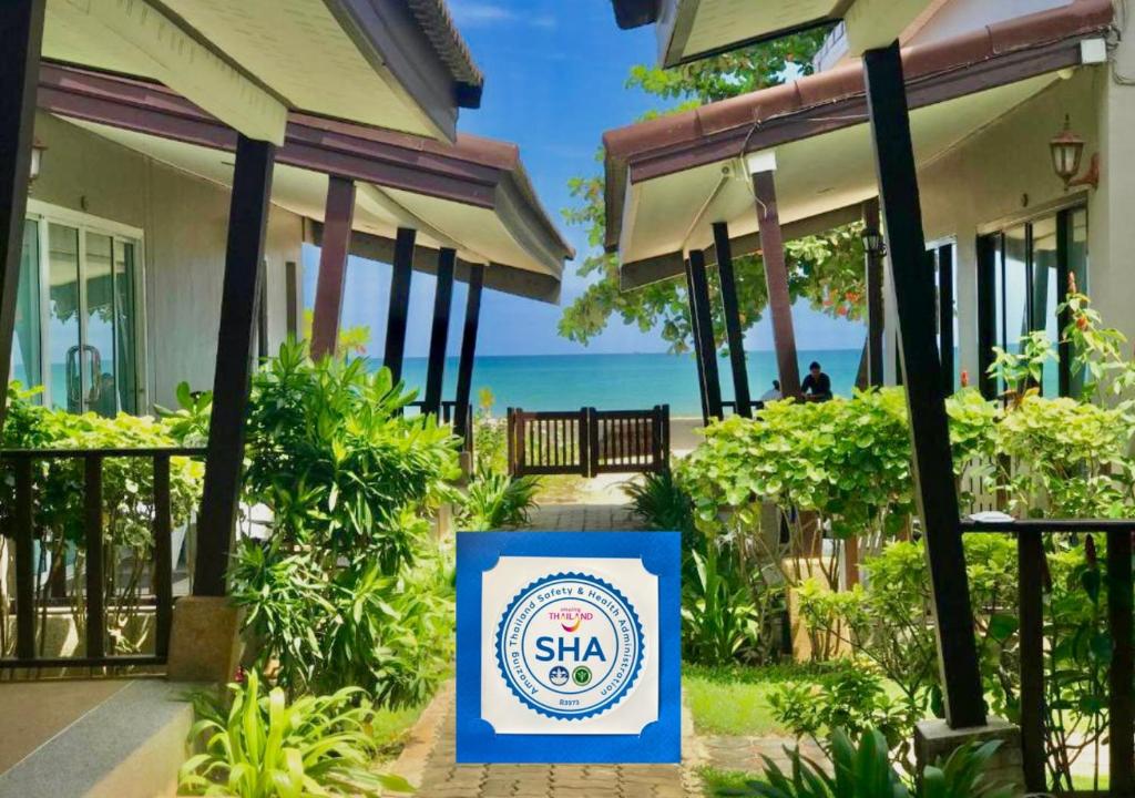 奈揚海灘的住宿－Dang Sea Beach Resort - SHA，背景是大海的建筑前的标志