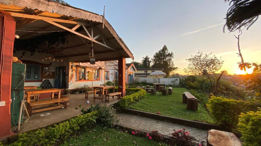 a patio with benches and tables in a backyard at The Birdhouse Backpackers Hostel in Coonoor