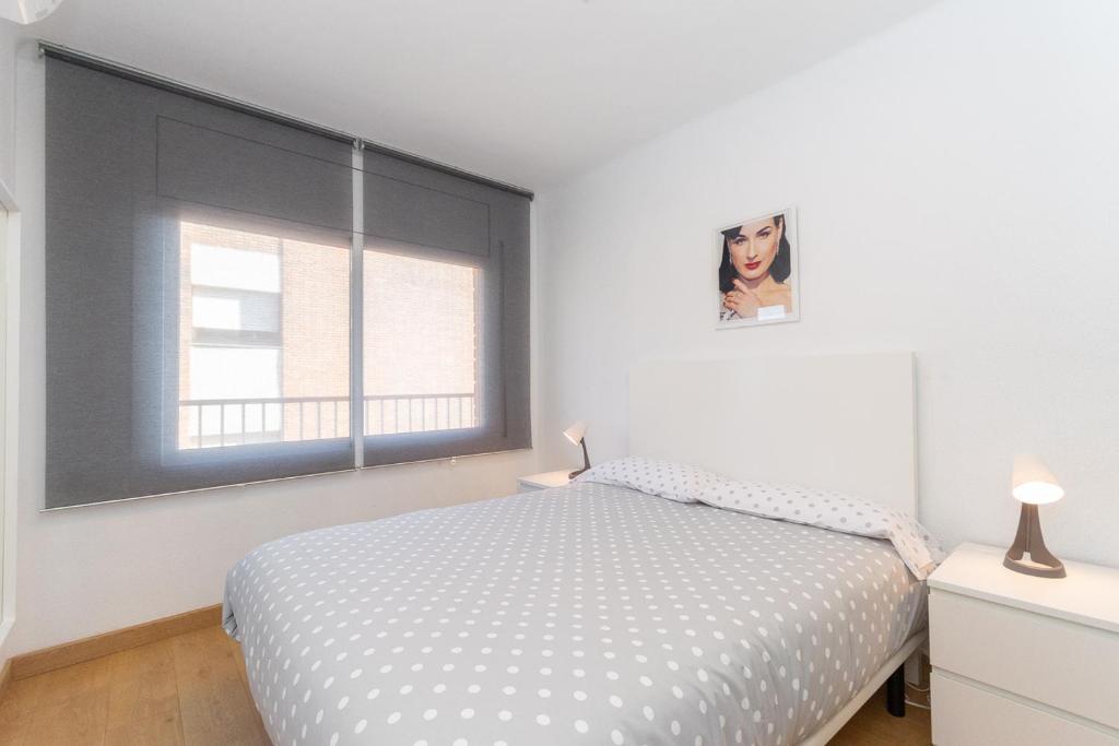 a white bedroom with a bed and a window at Cadillac Cornella Cozy 15 Min Airport Barcelona in Cornellà de Llobregat