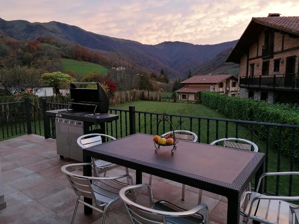 una mesa y sillas en un balcón con parrilla en Casa rural SOROA landetxea en Arantza