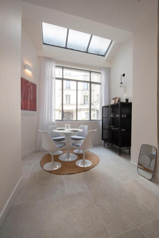 un salon avec une table et des chaises et une fenêtre dans l'établissement Cerisaie, à Paris