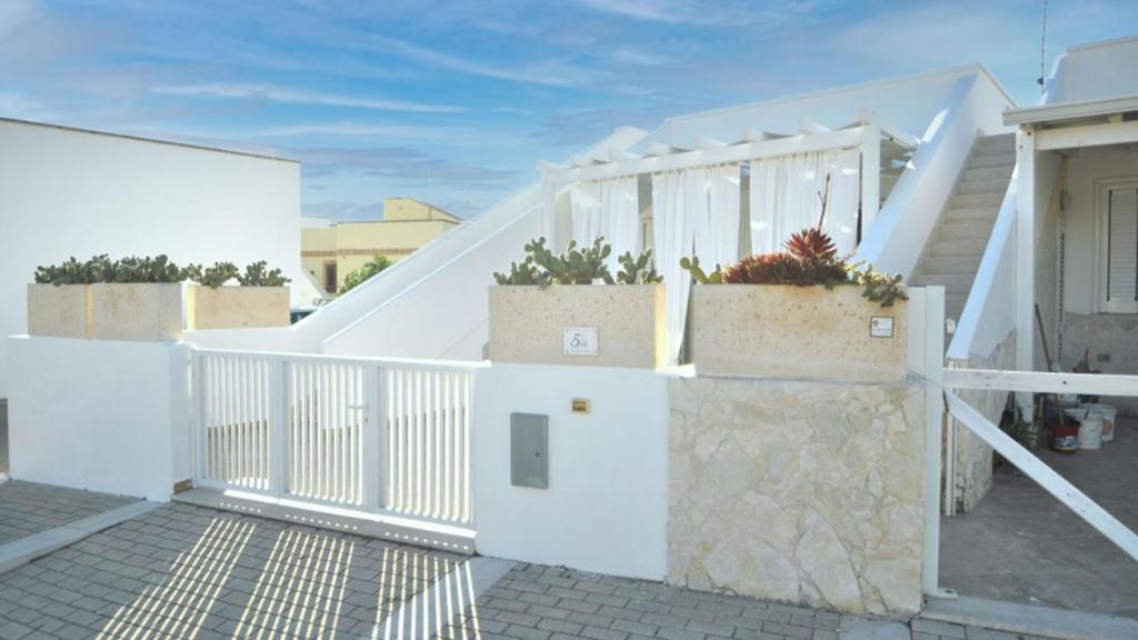a white fence with potted plants on top of it at Villetta Bianca by Salento Affitti in Torre San Giovanni Ugento