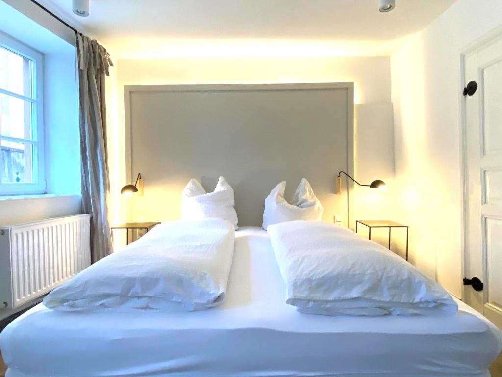una camera con 2 letti con lenzuola e cuscini bianchi di Living in History - Modern Country Cottage a Dudeldorf