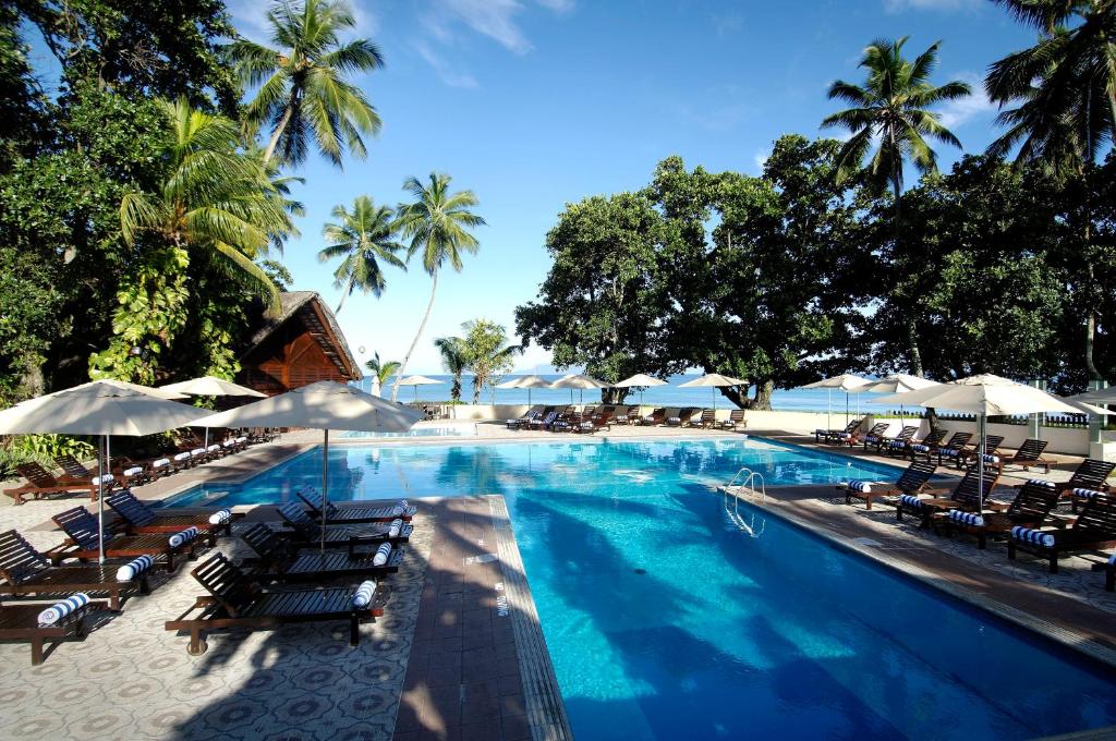 a beach area with a pool, chairs, and tables at Berjaya Beau Vallon Bay Resort & Casino in Beau Vallon