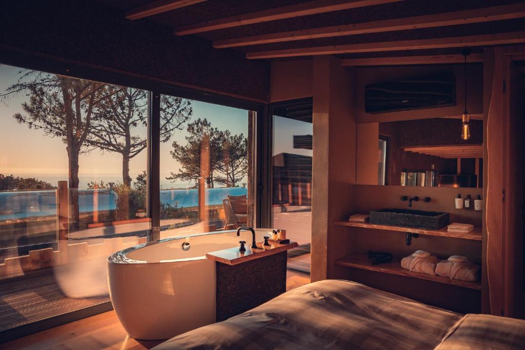 a bathroom with a bath tub and a large window at Charm Nature in Azoia