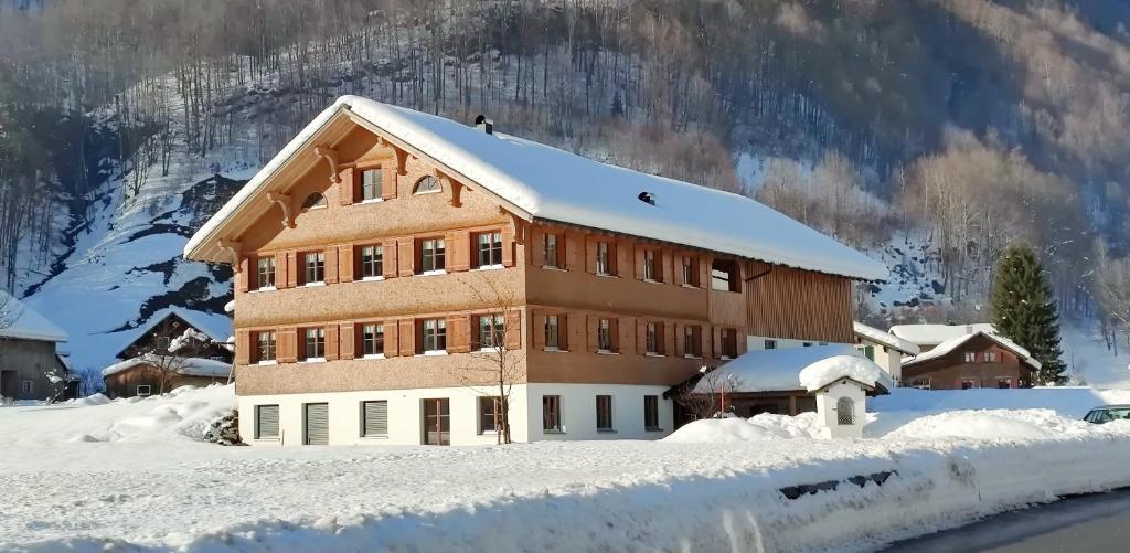 un edificio cubierto de nieve con una montaña en el fondo en Haus Schwendinger, en Mellau