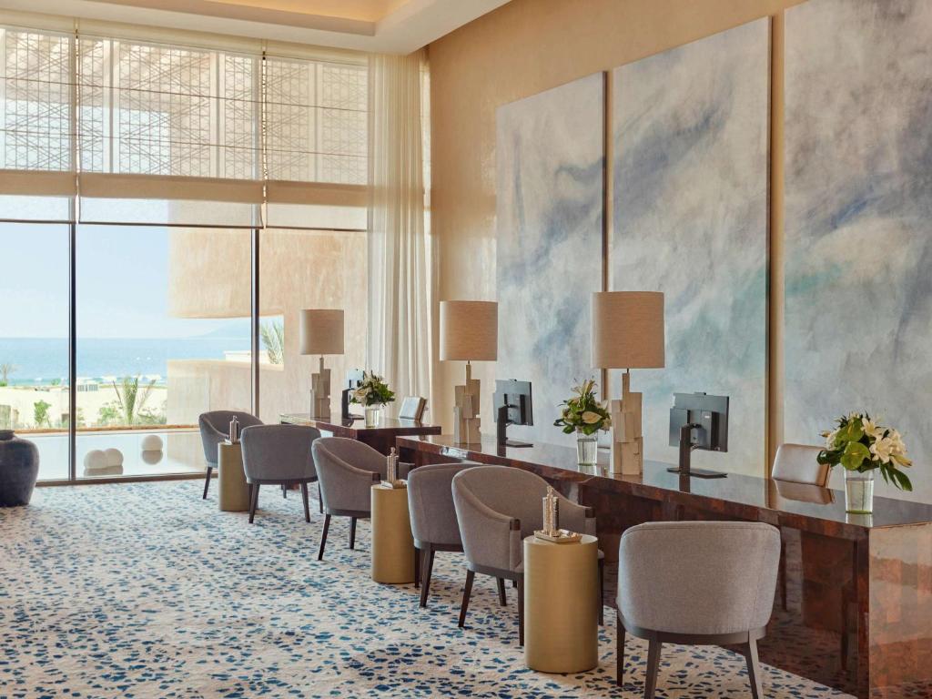 Fairmont Taghazout Bay في تغازوت: لوبي الفندق مع الكراسي والطاولات ولوحة كبيرة