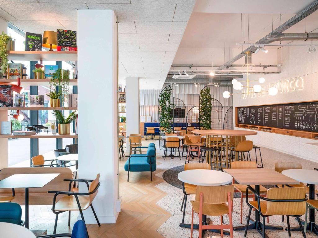 un restaurante con mesas y sillas y una pizarra en ibis Styles Paris Romainville, en Romainville