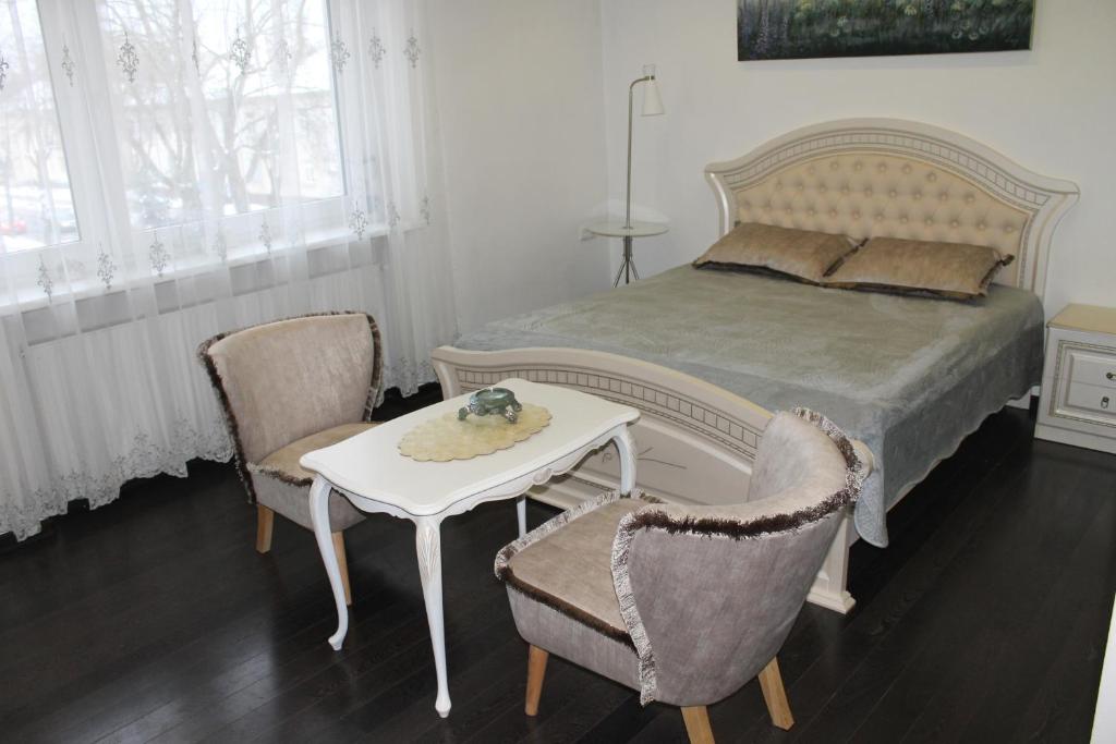 - une chambre avec un lit, deux chaises et une table dans l'établissement Apartamentai Flora, à Palanga