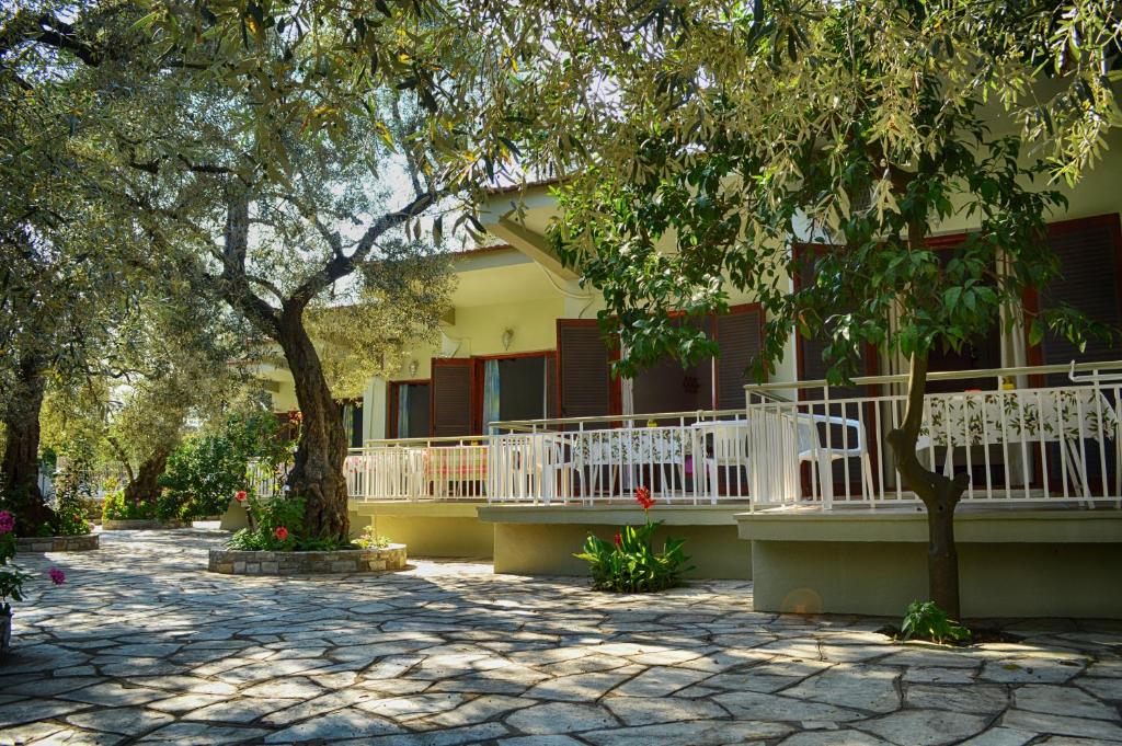 a building with a white porch and a tree at Guesthouse Irene in Afissos