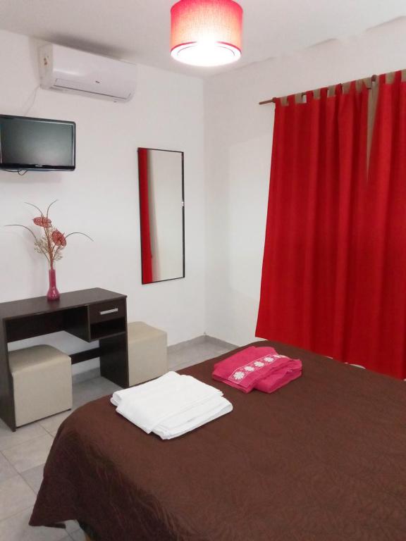 um quarto com uma cama com uma cortina vermelha e uma secretária em Miró departamento con cochera em Villa María