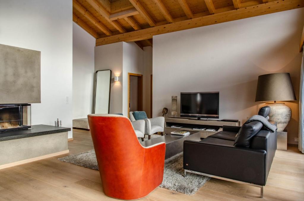 a living room with a black couch and a red chair at Apartment Silbersee - GRIWA RENT AG in Grindelwald