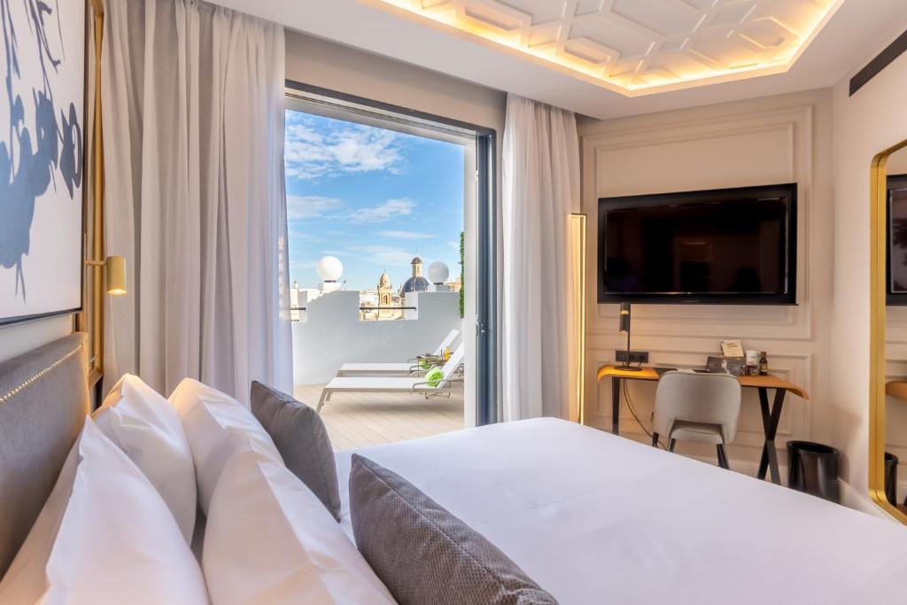 pokój hotelowy z łóżkiem i dużym oknem w obiekcie L&H Gran Vía Valencia w Walencji