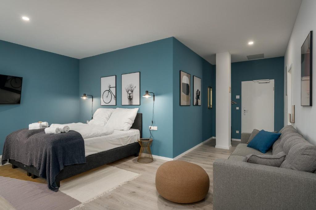 リップシュタットにあるBRIGHT Lippstadt Klusetorの青い壁のベッドルーム1室、ベッド1台、ソファが備わります。