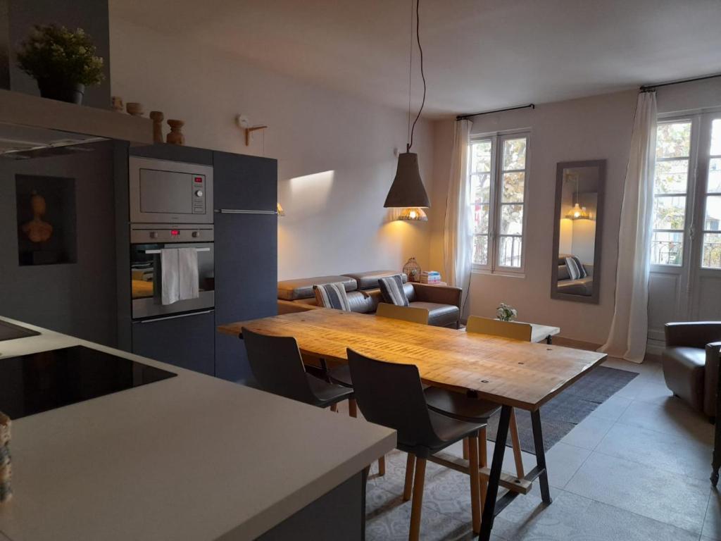 a kitchen and living room with a wooden table at Apparts Et Lofts Bistrot Des Alpilles in Saint-Rémy-de-Provence