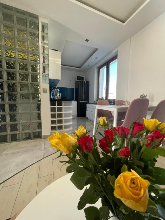 a vase of yellow and red flowers sitting on a table at LUXURY BLUE APARTMENT by Marta in Radom