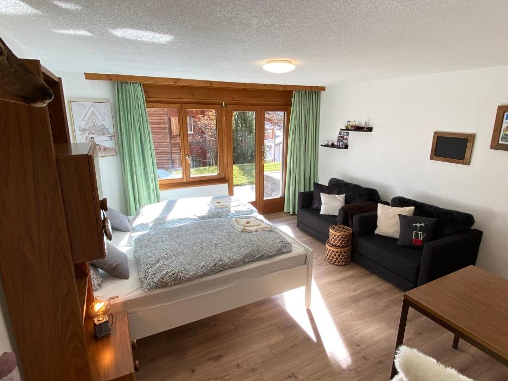 een slaapkamer met een bed en een bank bij Haus Alpalin - 2 adjacent studios 'Mischabel', cosy, central, 4p in Saas-Fee