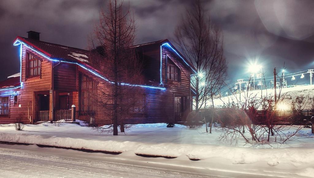 una cabaña de madera con luces azules en la nieve en Dmitrov Golf Resort быв Сорочаны, en Kurovo