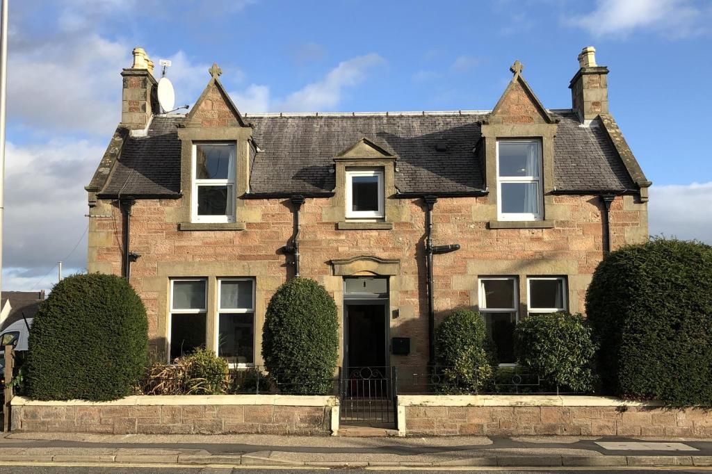 ein altes Backsteinhaus mit schwarzem Dach in der Unterkunft Winmar in Inverness