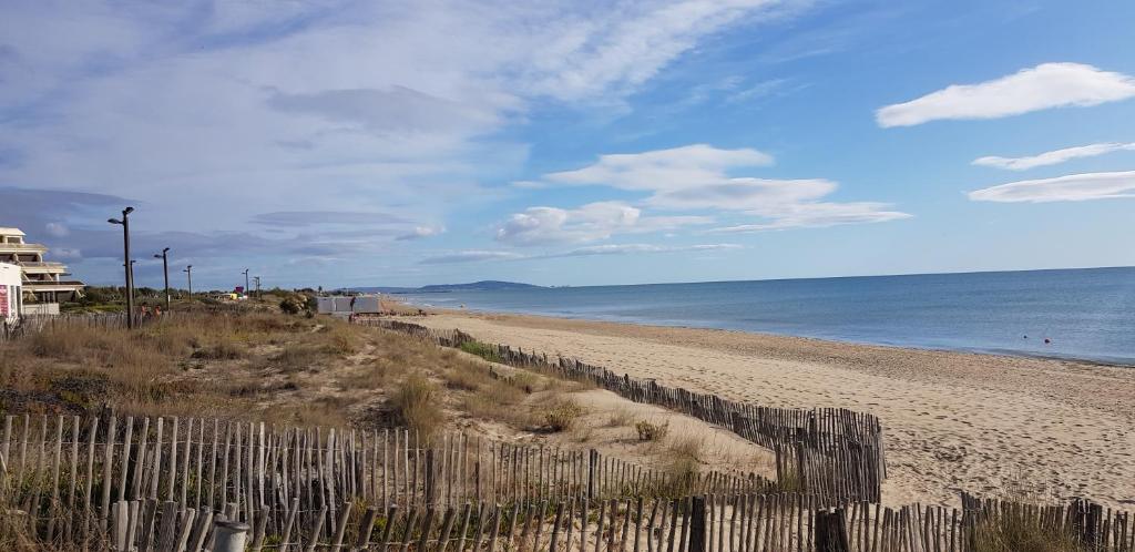 - une plage avec une clôture en bois et l'océan dans l'établissement Villa Naturiste NATURE Héliovillage 104, au Cap d'Agde