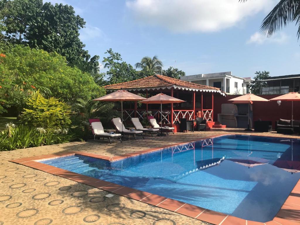 einen Pool mit Stühlen und Sonnenschirmen auf einer Terrasse in der Unterkunft Vila Marilyn in São Tomé