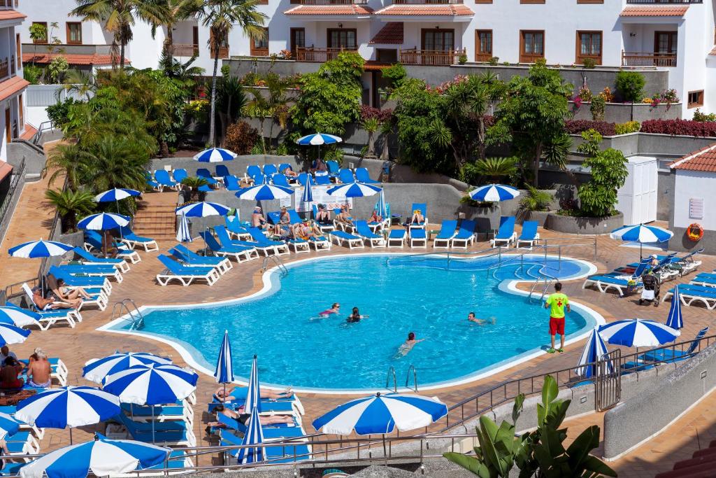 une piscine dans un hôtel avec des parasols bleus et blancs dans l'établissement Apartamentos Casablanca, à Puerto de la Cruz