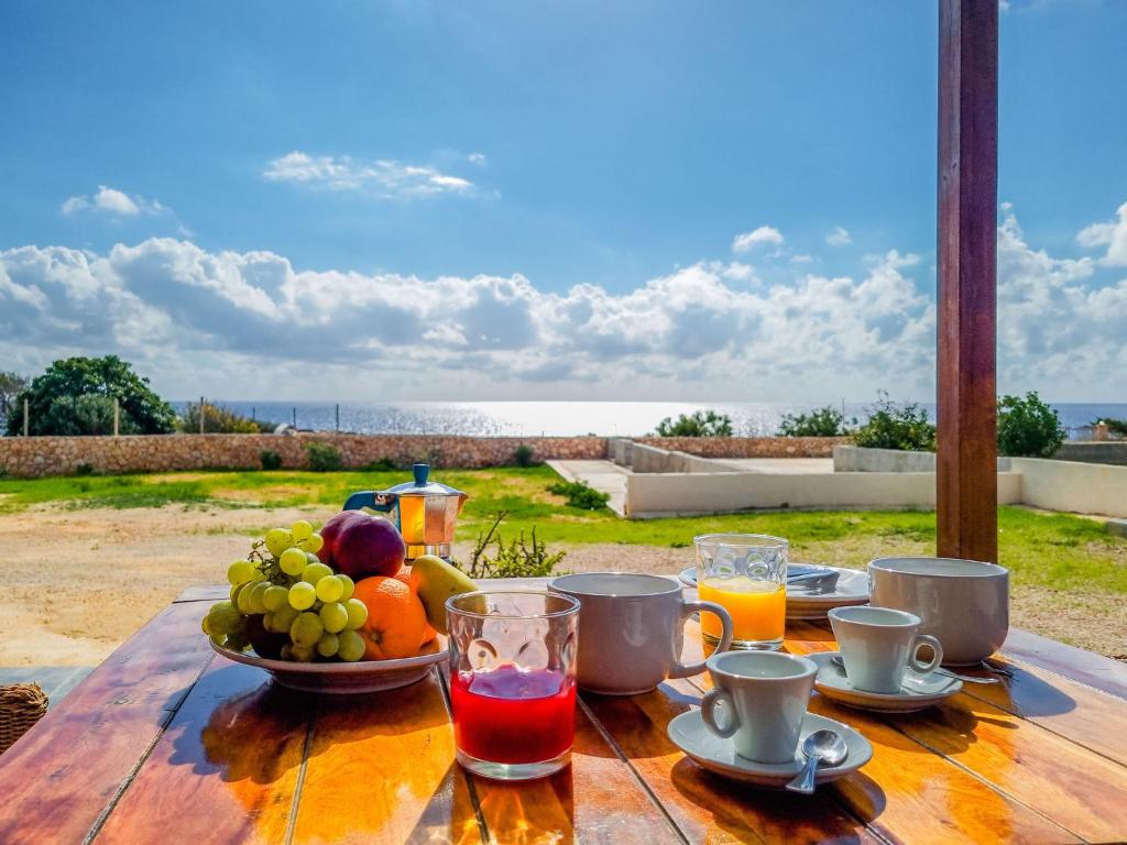 a wooden table with a bowl of fruit and juice at Holiday Residence La Madonnina in Lampedusa