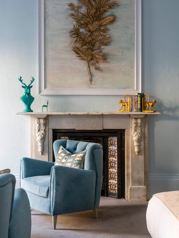 a living room with a blue chair and a fireplace at The Queensberry Hotel in Bath