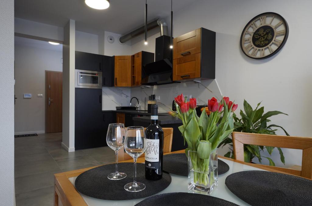 a dining room table with wine glasses and red tulips at Apartament przy Plantach in Nowy Sącz