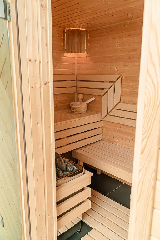 Warm wooden sauna interior with tiered benches, a ladle bucket, and a stone heater.