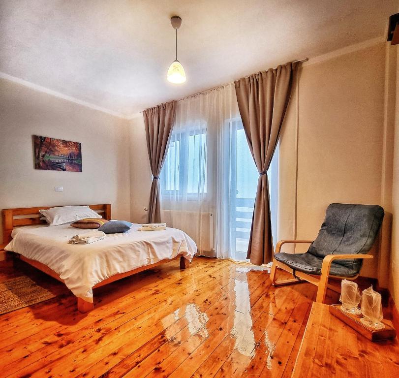 a bedroom with a bed and a chair and a window at Pensiunea La Bunica in Rugineşti