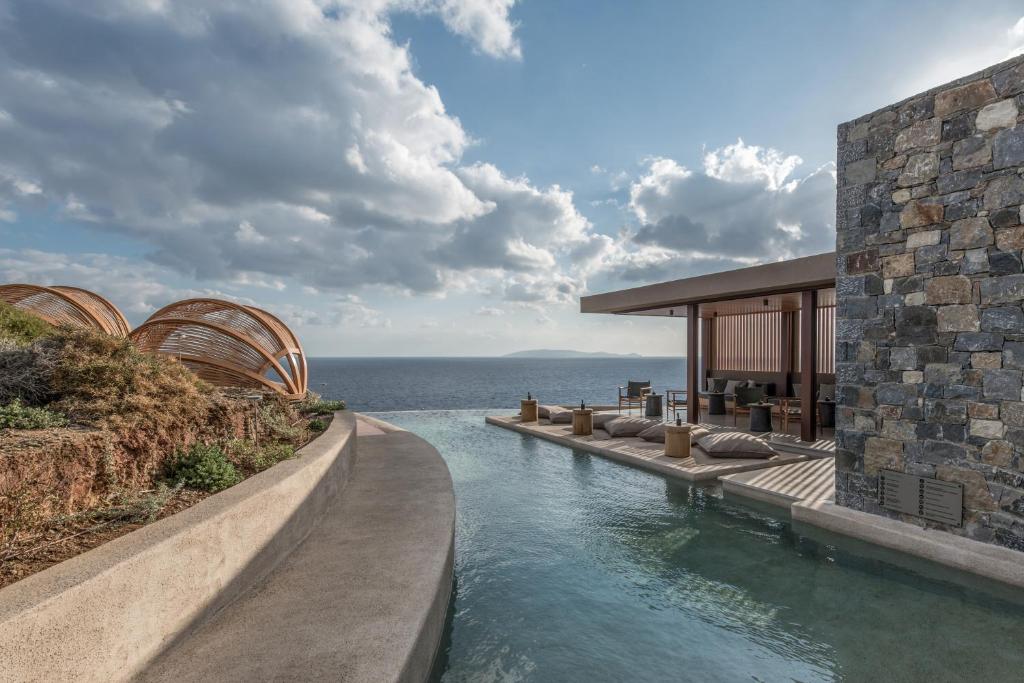 a house with a swimming pool next to the ocean at Acro Suites - A Wellbeing Resort in Agia Pelagia