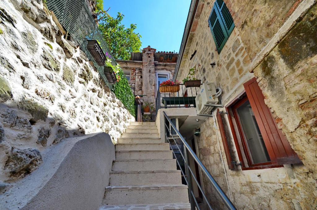 a set of stairs leading up to a building with a red door at Apartments Historic Stone House in Kotor