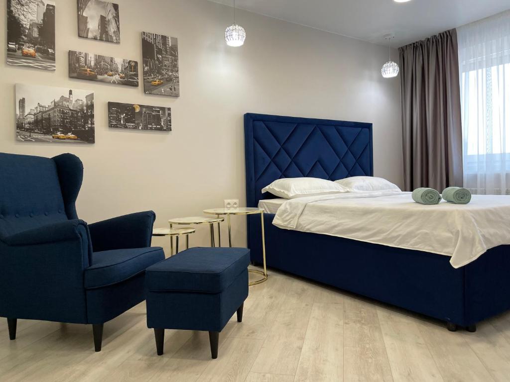 una camera con un letto blu e una sedia di Krivenko 49 Str by Slissenko Inn a Pavlodar