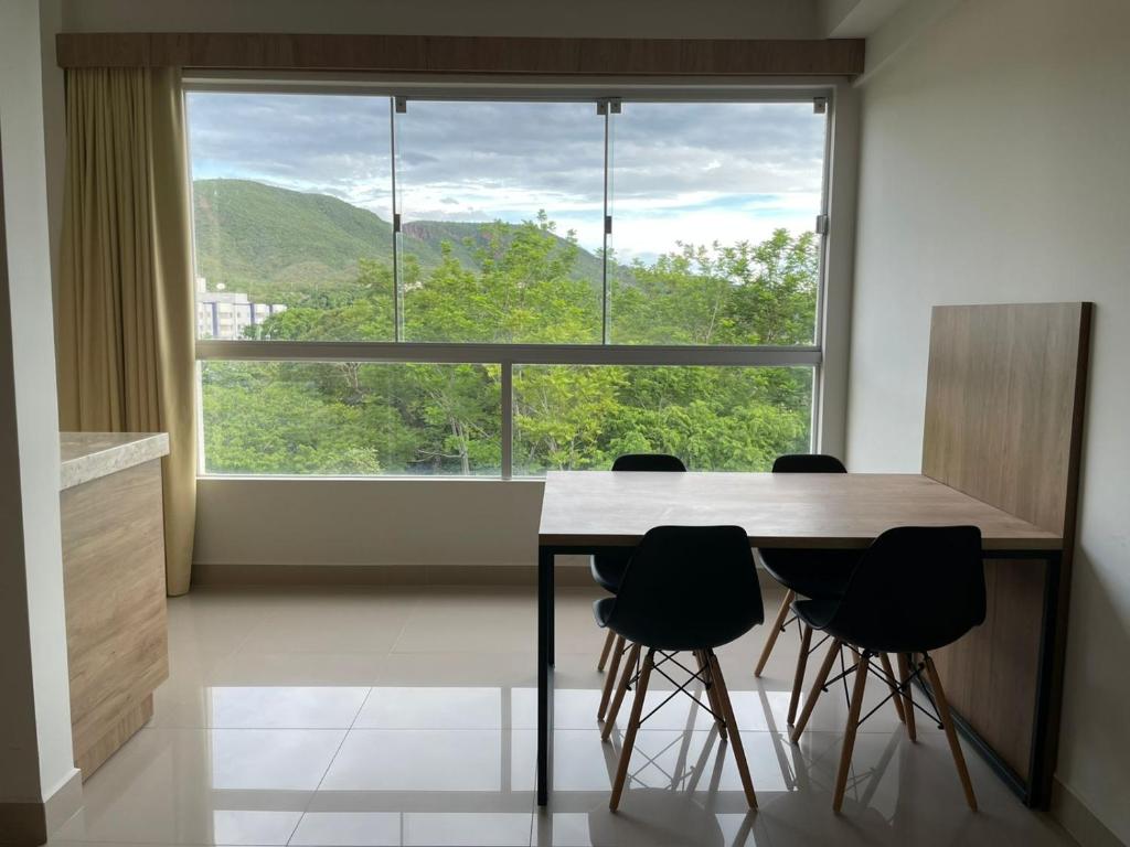 einen Tisch und Stühle in einem Zimmer mit einem großen Fenster in der Unterkunft Park Veredas, Rio Quente , com vista para a montanha in Rio Quente