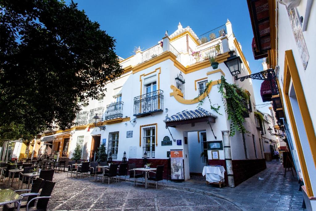 a white building with tables and chairs on a street at Hotel Boutique Elvira Plaza in Seville