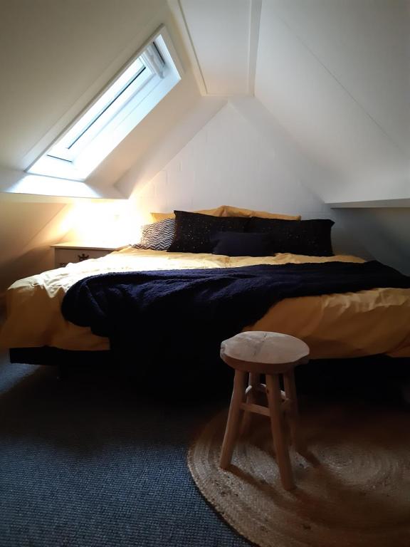 a bedroom with a bed with a stool next to it at Vakantiehuis aan het Bos - langs de Tulpenroute! in Bant